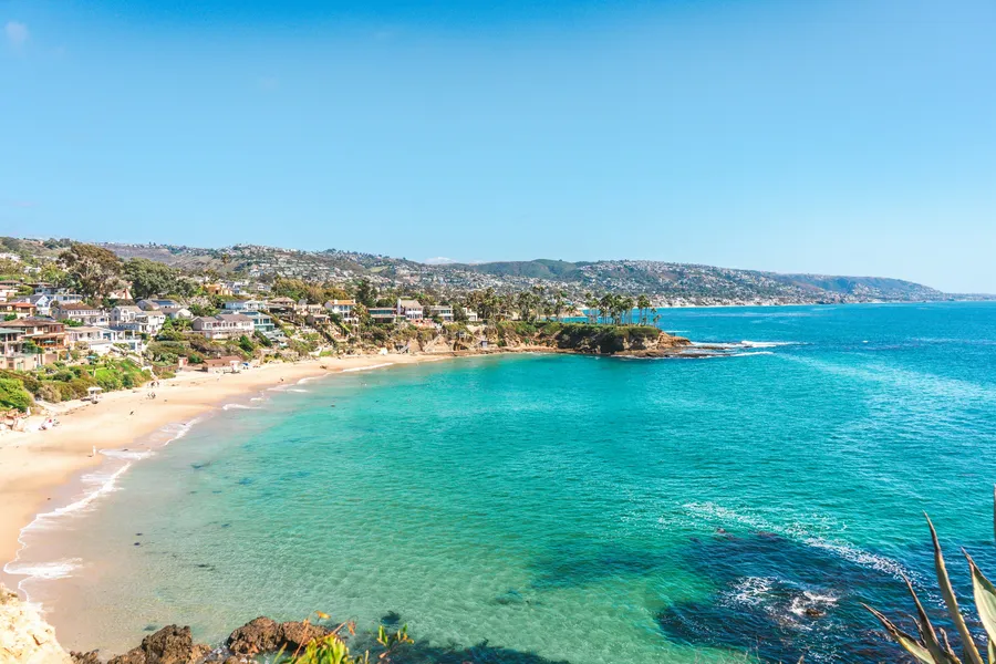 Turquoise water and a sandy cove below the coastal homes of Laguna Beach, viewed from Crescent Bay Point Park.